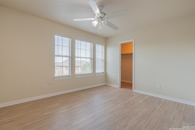 empty room with ceiling fan and light hardwood / wood-style floors