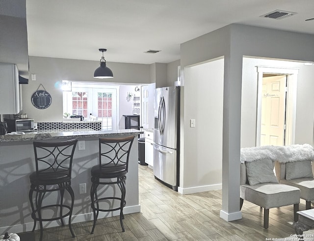 kitchen featuring a kitchen bar, french doors, light hardwood / wood-style floors, kitchen peninsula, and appliances with stainless steel finishes