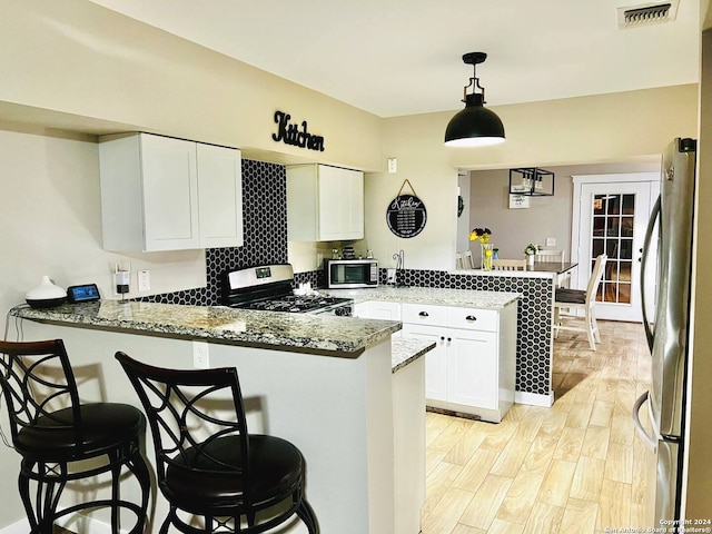 kitchen featuring light hardwood / wood-style flooring, kitchen peninsula, appliances with stainless steel finishes, and white cabinets