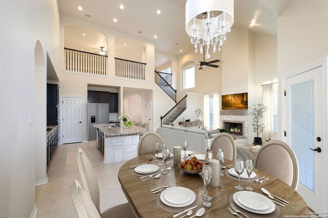 7270 Lunar Eclipse, Converse, TX 78109 - dining room with a towering ceiling, ceiling fan, a fireplace, arched walkways, and light tile patterned floors