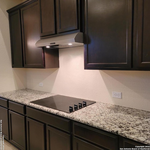 kitchen with light stone counters, black electric stovetop, and dark brown cabinetry