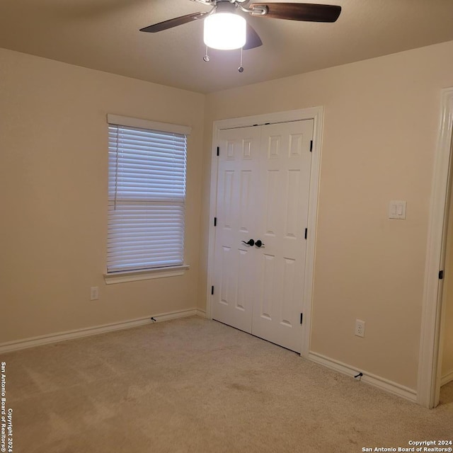 unfurnished bedroom with ceiling fan, a closet, and light carpet