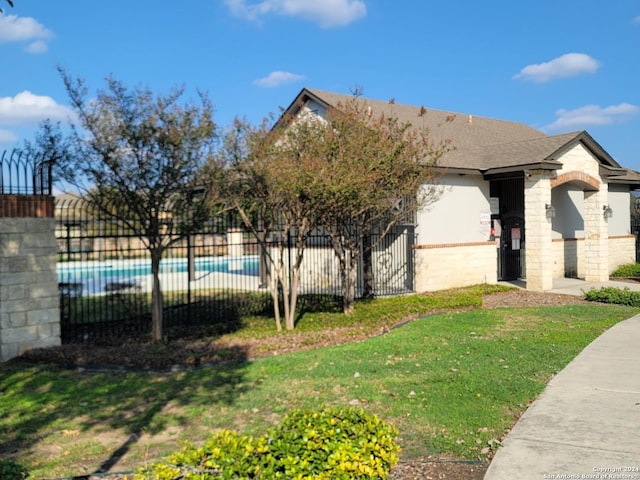 exterior space with a front yard and a fenced in pool