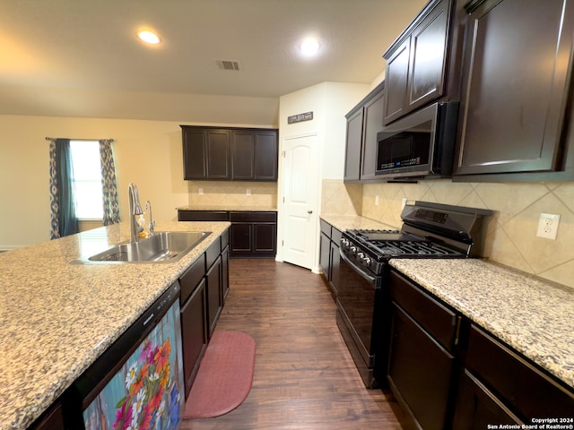 kitchen with dark wood-type flooring, sink, tasteful backsplash, light stone countertops, and appliances with stainless steel finishes