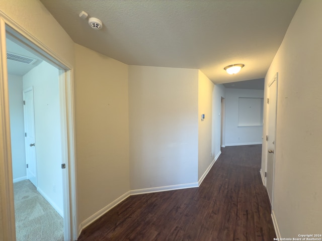 hallway with dark hardwood / wood-style floors and a textured ceiling