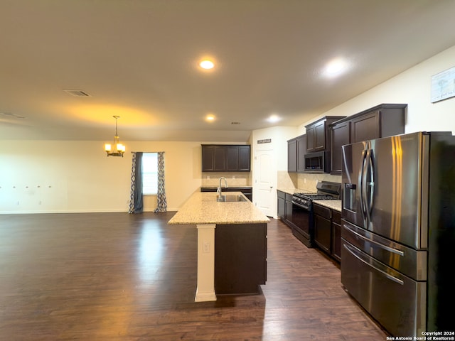 kitchen featuring dark wood-type flooring, appliances with stainless steel finishes, sink, and a kitchen island with sink