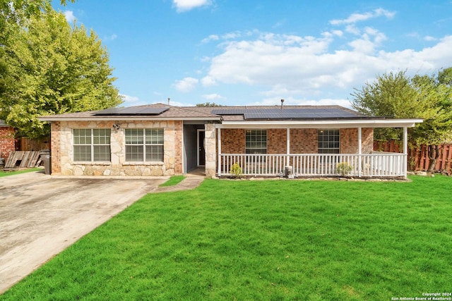 ranch-style house with covered porch, a front yard, and solar panels