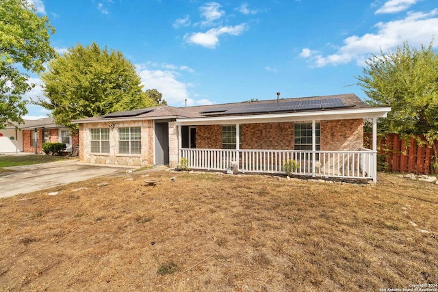 single story home featuring a front lawn, a porch, and solar panels