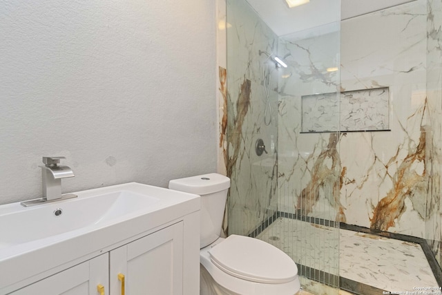 bathroom featuring toilet, a tile shower, and vanity