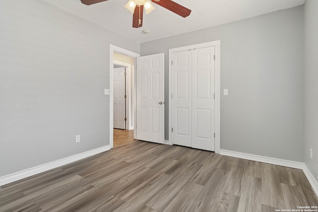 unfurnished bedroom with ceiling fan, a closet, and hardwood / wood-style flooring