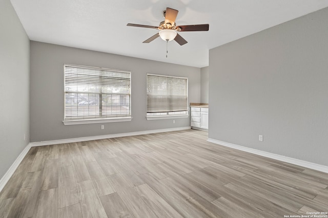 empty room with ceiling fan and light hardwood / wood-style flooring