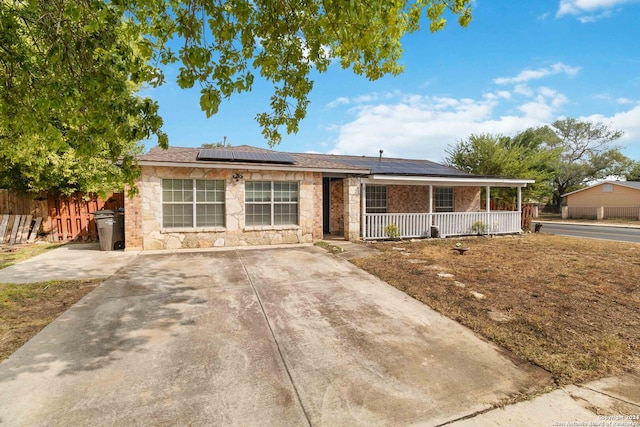 ranch-style house featuring a porch and solar panels