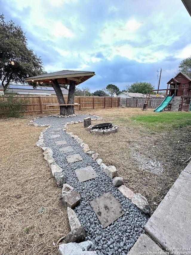 view of yard with an outdoor fire pit and a playground