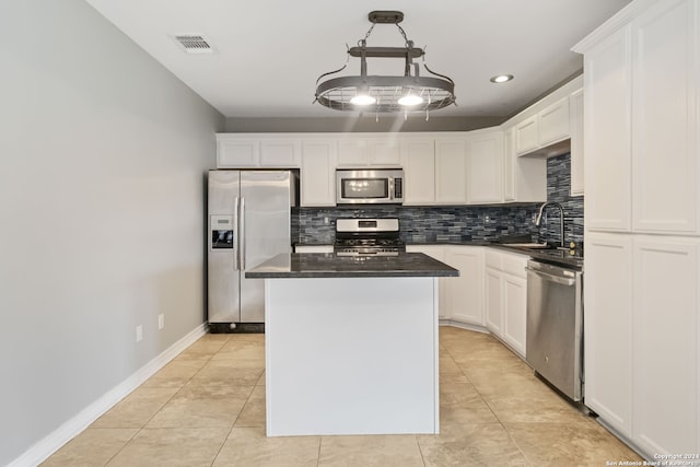 kitchen with appliances with stainless steel finishes, hanging light fixtures, a kitchen island, white cabinets, and sink