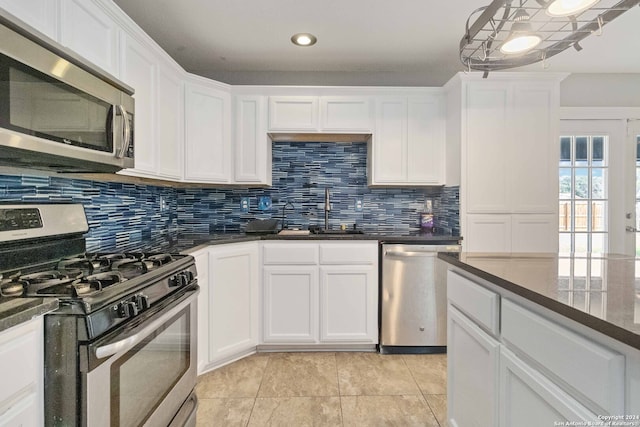 kitchen with tasteful backsplash, sink, white cabinetry, stainless steel appliances, and light tile patterned floors