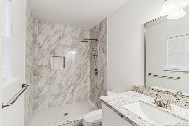 bathroom with tiled shower, toilet, and vanity