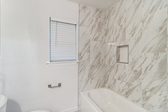 bathroom featuring toilet and tiled shower / bath combo