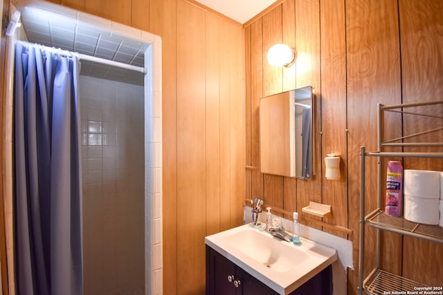 bathroom with walk in shower, wood walls, and vanity