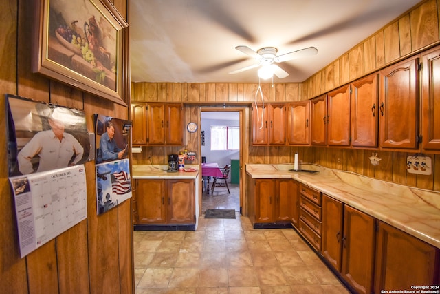 kitchen with ceiling fan and wooden walls