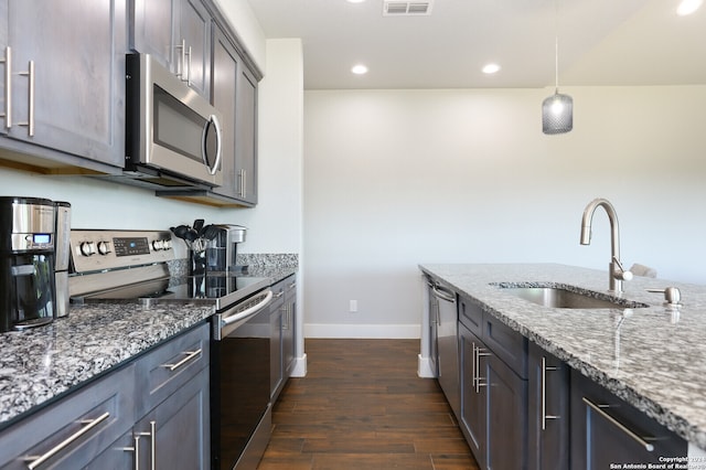 kitchen featuring dark wood-type flooring, sink, light stone countertops, appliances with stainless steel finishes, and decorative light fixtures