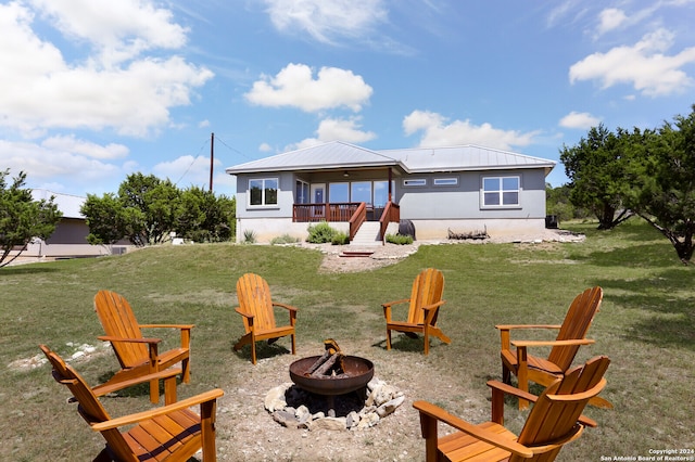 rear view of house with an outdoor fire pit and a lawn