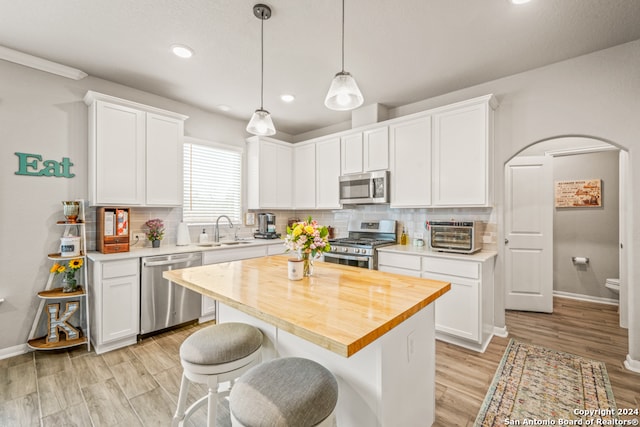 kitchen with white cabinetry, appliances with stainless steel finishes, backsplash, sink, and a center island