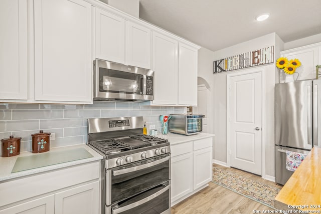 kitchen featuring light hardwood / wood-style floors, white cabinetry, appliances with stainless steel finishes, and tasteful backsplash