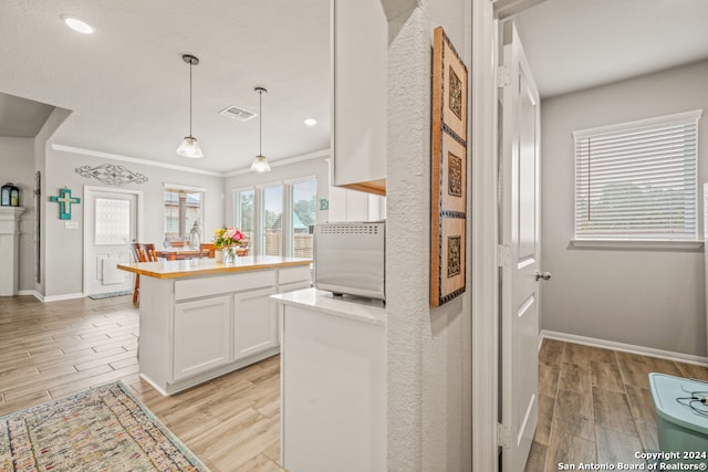 kitchen featuring white cabinetry, hanging light fixtures, and light hardwood / wood-style flooring