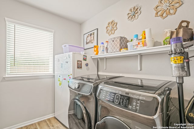 laundry area with washing machine and clothes dryer and light hardwood / wood-style flooring