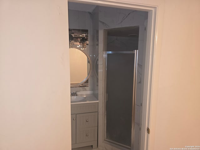 bathroom featuring a shower with shower door and vanity