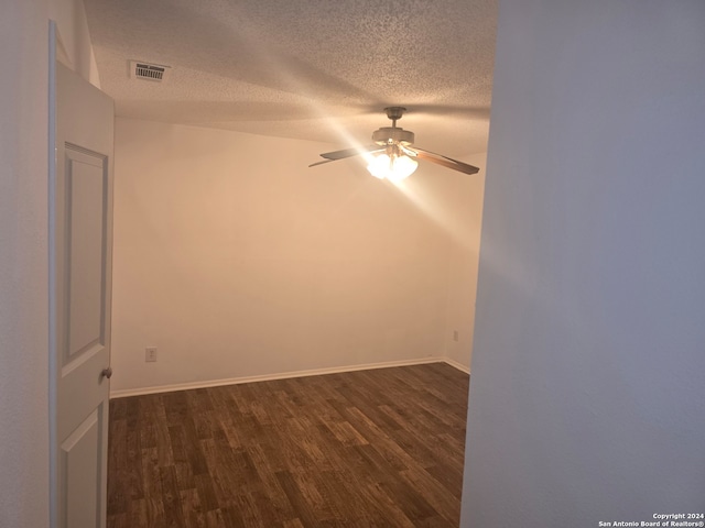 spare room featuring dark hardwood / wood-style flooring, a textured ceiling, and ceiling fan