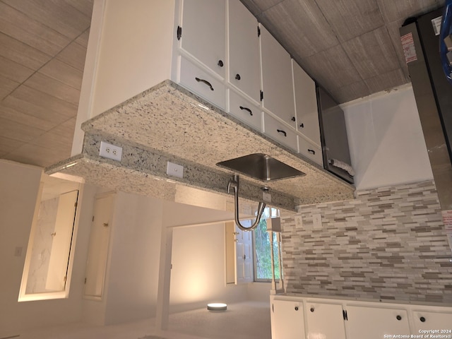 kitchen with white cabinetry, light stone counters, and tasteful backsplash