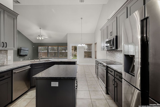 kitchen featuring vaulted ceiling, stainless steel appliances, decorative backsplash, and a kitchen island