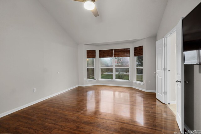 empty room with ceiling fan, dark hardwood / wood-style flooring, and vaulted ceiling