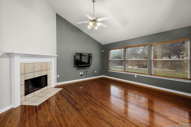 unfurnished living room featuring hardwood / wood-style flooring, ceiling fan, high vaulted ceiling, and a tiled fireplace