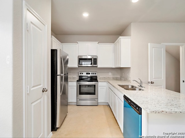 kitchen with white cabinets, appliances with stainless steel finishes, sink, and light stone countertops