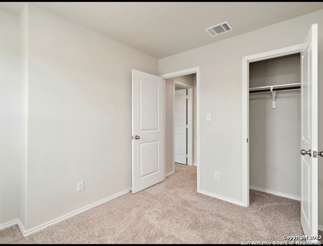 unfurnished bedroom with a closet and light carpet