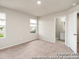 unfurnished bedroom featuring connected bathroom and light carpet