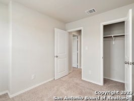 unfurnished bedroom featuring a closet and light carpet