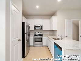 kitchen with kitchen peninsula, appliances with stainless steel finishes, sink, and white cabinets