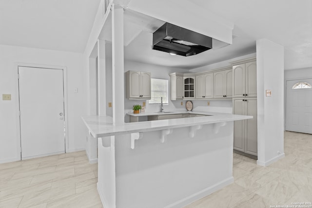 kitchen with a kitchen breakfast bar, gray cabinets, sink, and a center island