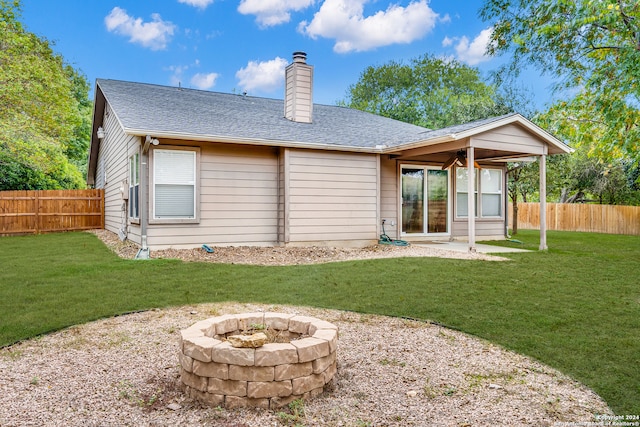 rear view of property featuring a fire pit and a lawn