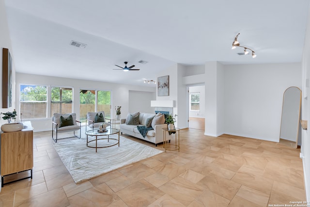 living room featuring ceiling fan, vaulted ceiling, and a tiled fireplace