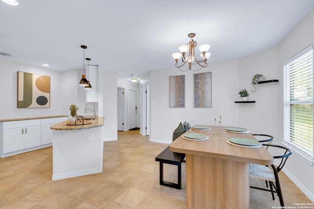 kitchen featuring white cabinetry, light stone counters, kitchen peninsula, a chandelier, and pendant lighting