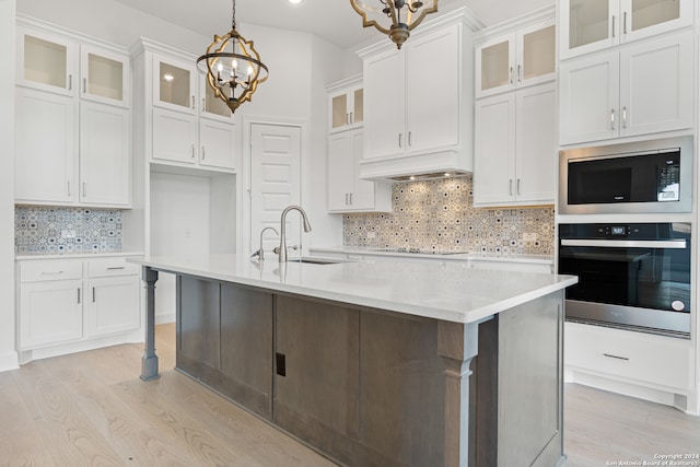 kitchen with appliances with stainless steel finishes, decorative light fixtures, sink, an island with sink, and white cabinets