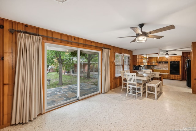 unfurnished dining area featuring ceiling fan and wooden walls