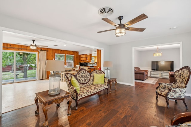 living room featuring hardwood / wood-style floors, ceiling fan, and wood walls