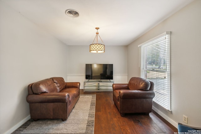 living room with dark hardwood / wood-style floors and a healthy amount of sunlight