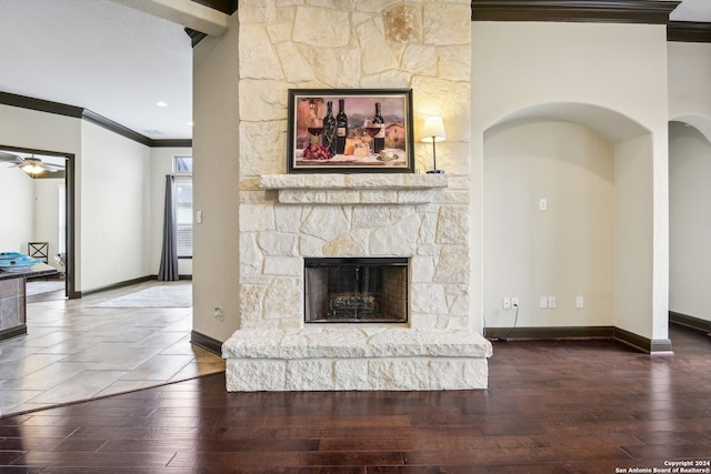 unfurnished living room featuring a fireplace, wood-type flooring, ceiling fan, and ornamental molding