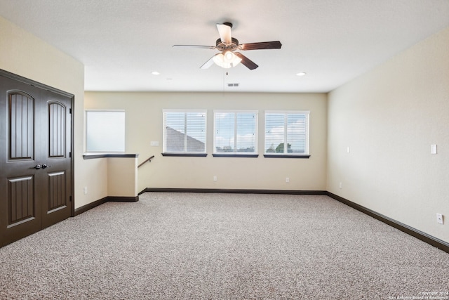 empty room with ceiling fan, plenty of natural light, and carpet floors